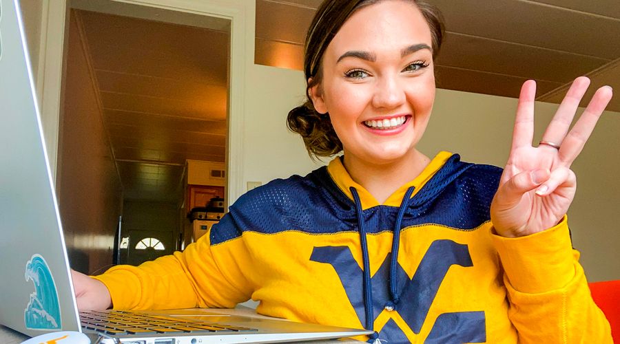 Winter student at home wearing a WVU sweatshirt and using her laptop.